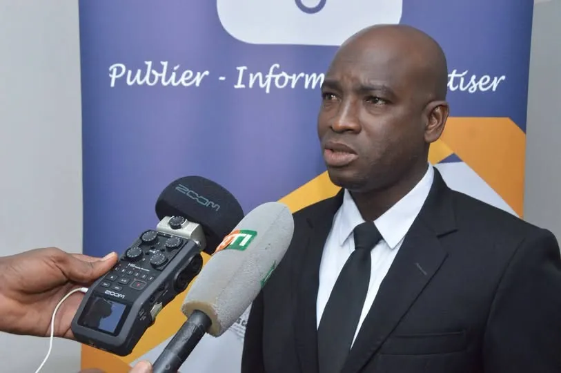Un intervenant répond aux questions de la presse, micros tendus.
